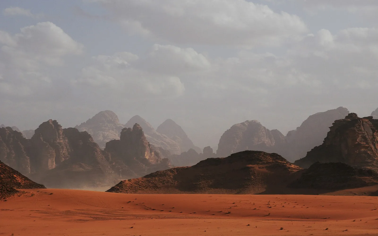 Red sand dunes and towering sandstone cliffs in the Wadi Rum desert under a clear sky