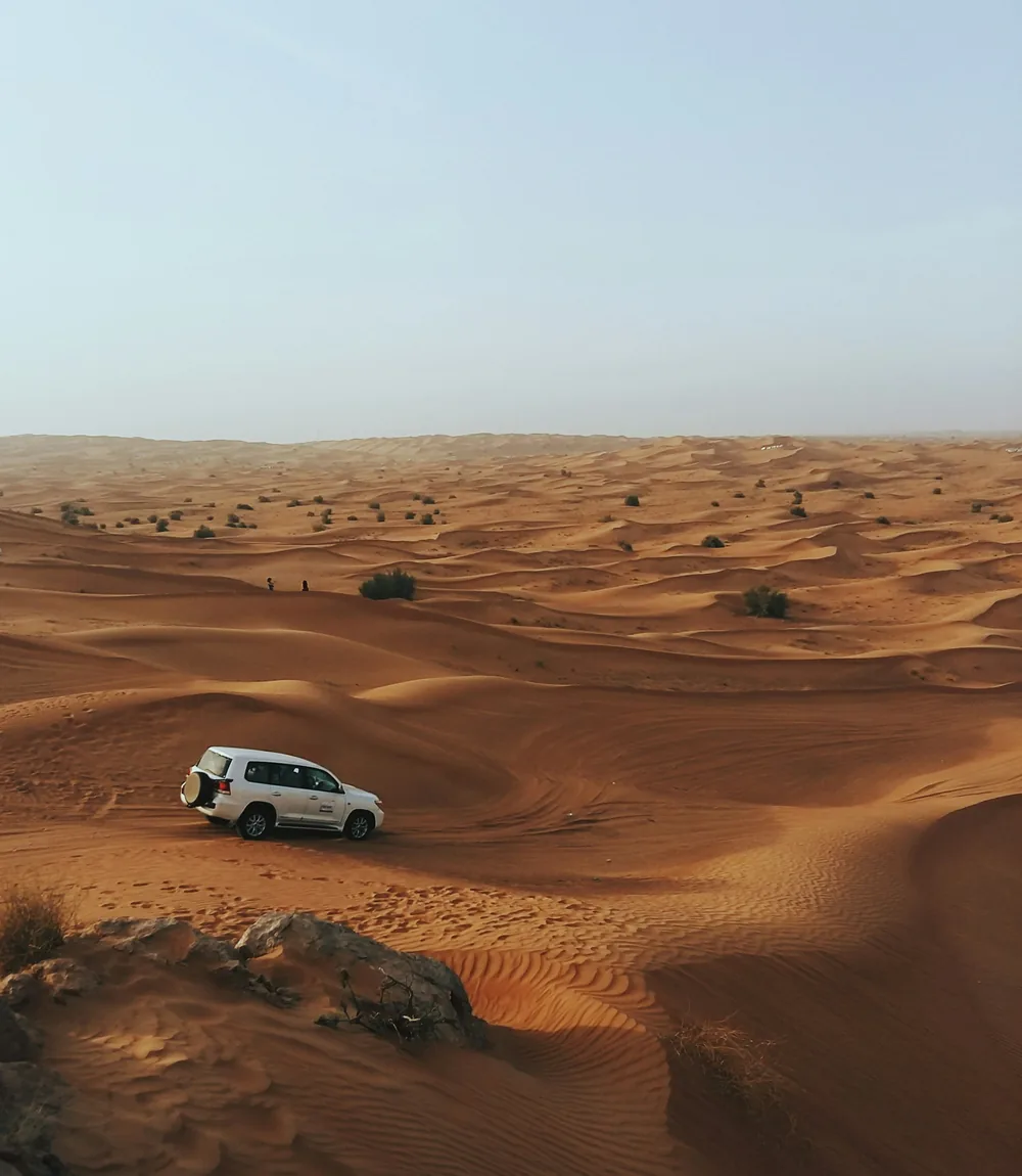 An open 4x4 jeep crossing the red desert sand of Wadi Rum